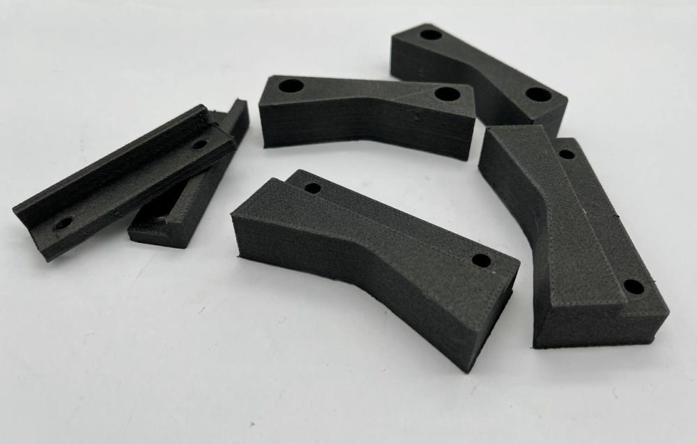 Mehrere individuell konstruierte schwarze Funktionsbauteile aus dem 3D-Druck